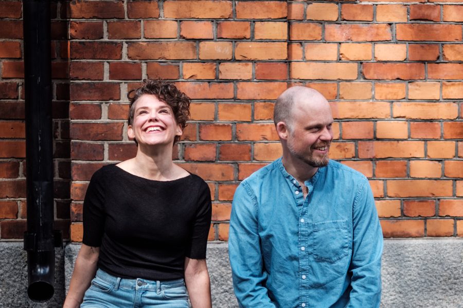Maja Heurling and Ola Sandström sitting in front of a red brick wall